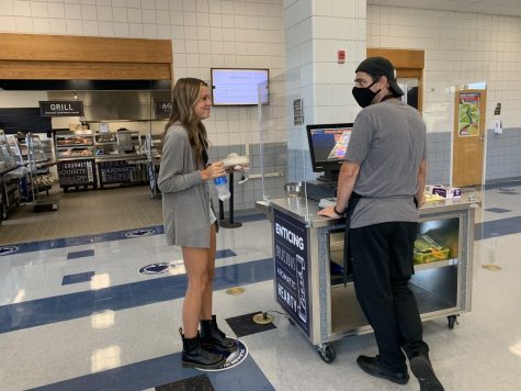 Senior Kylee Lescas talks to cafeteria worker Adam after buying her lunch. Due to the new grant, more students are buying school lunch which makes the lines a lot longer. “We are going through roughly 400-500 more full meals a day with this grant,” Head Chef Jon Harbaugh said.