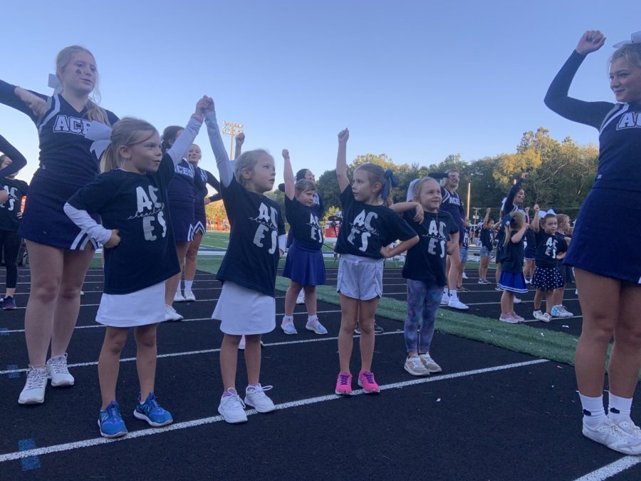 Ella Kunar leads the first grade cheerleaders on the track as they cheer on the football team. 