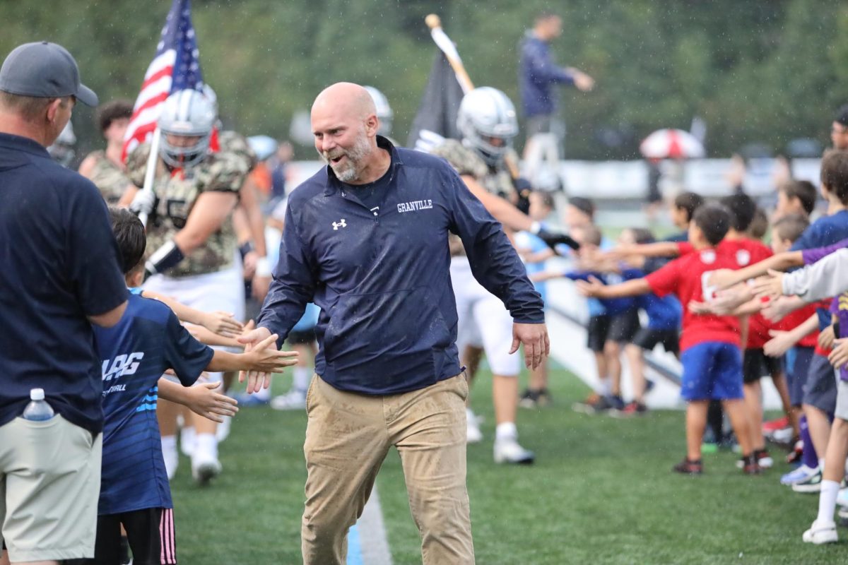 New head football coach, Heath Hinton getting ready to defeat Johnstown last Friday night. High-fiving the REC team while the football players follow. 