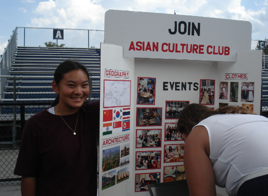 Junior Annabel Burt at the club fair standing beside her booth and encouraging students to join the Asian Culture Club. 