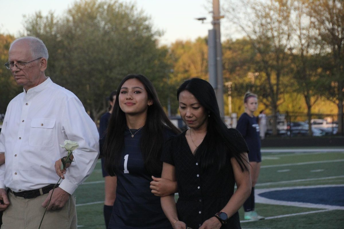 Alana Snyder smiles big for her soccer senior night, holding the arms of her mother and father. Alana has a fun night playing her last LCL champ game as a senior.