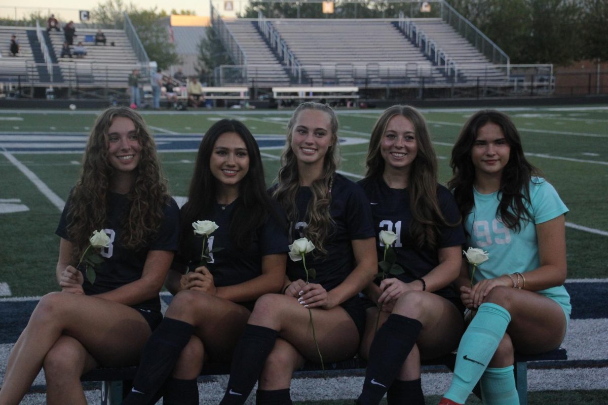 Seniors Audrey Ames, Alana Snyder, Ayla Cook, Raegan Timmons, and Sydney Lauffer smile bright while sitting on the senior bench. These seniors had a wonderful season with each other growing as a team. 