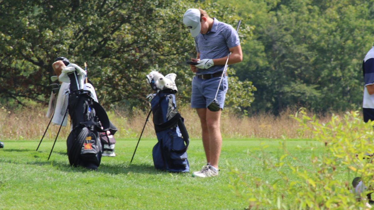 Senior Chase Holtzapple waits for his opponents to finish putting.