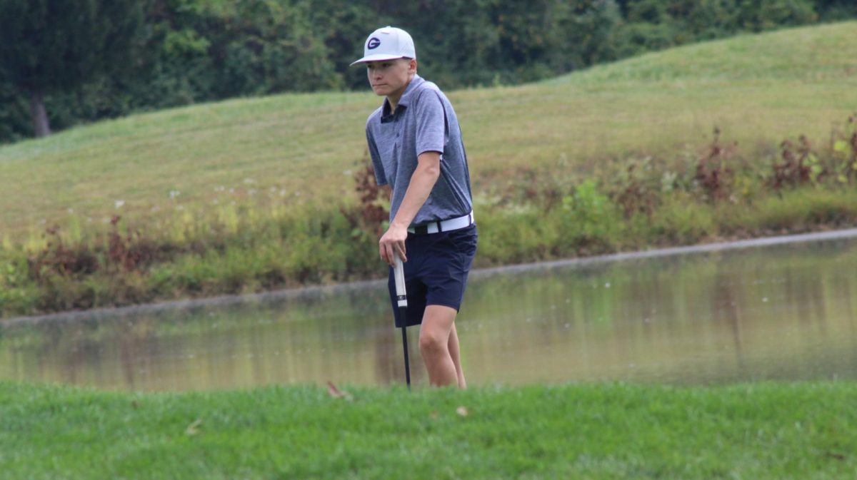 Freshmen Hudson Hall watches other golfers as he prepares to putt his ball. 
