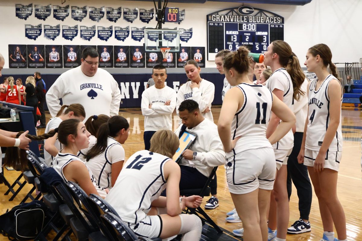 Coach Kelan Thompson writes out at play during a timeout. The girls ended up scoring and winning the game.
