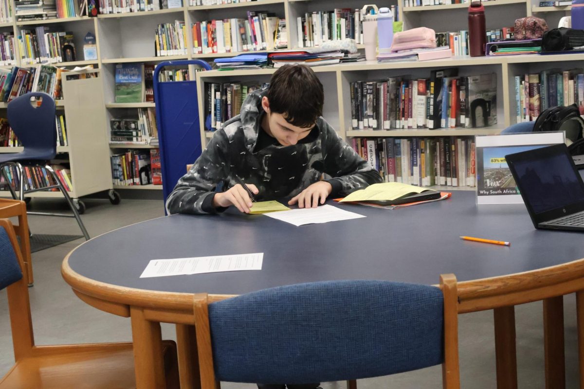 Cooper Beach (10) takes notes as he reads one of the stations in Mrs. Henderson's class. 