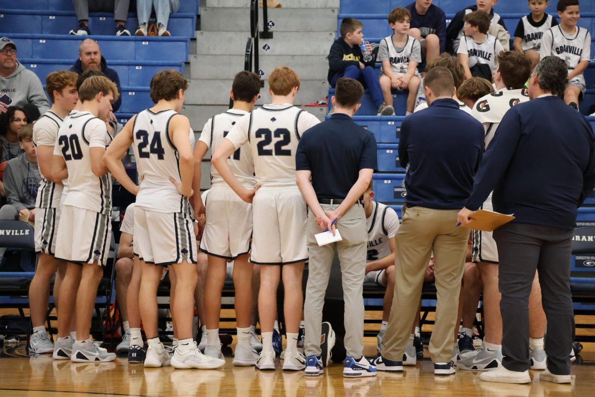 The team gathers around the starters to hear the next play during a quick timeout. The coaches discussed their game plan and made final adjustments with the players.