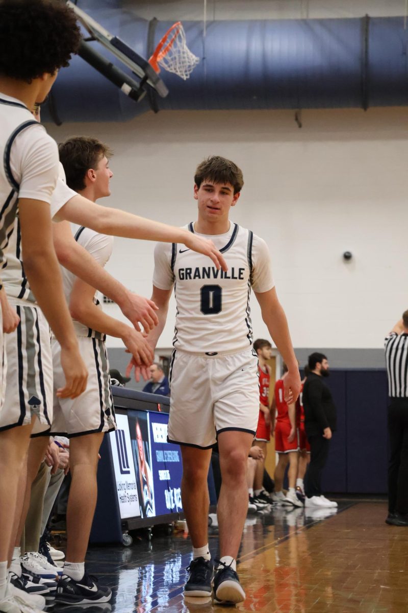 Senior Charlie Wright high fives his teammates while coming off the court. The boys showed great sportsmanship throughout the game.