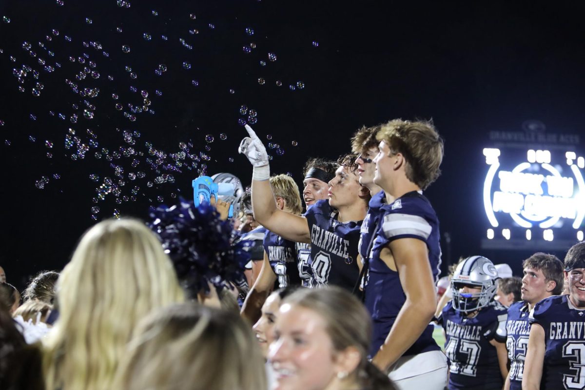 Luke Sanchez (12) pops bubbles while lining up to chant the Granville alma mater. As a tradition the Blue Ace players and student section come together to celebrate the win against Utica for during their homecoming game.