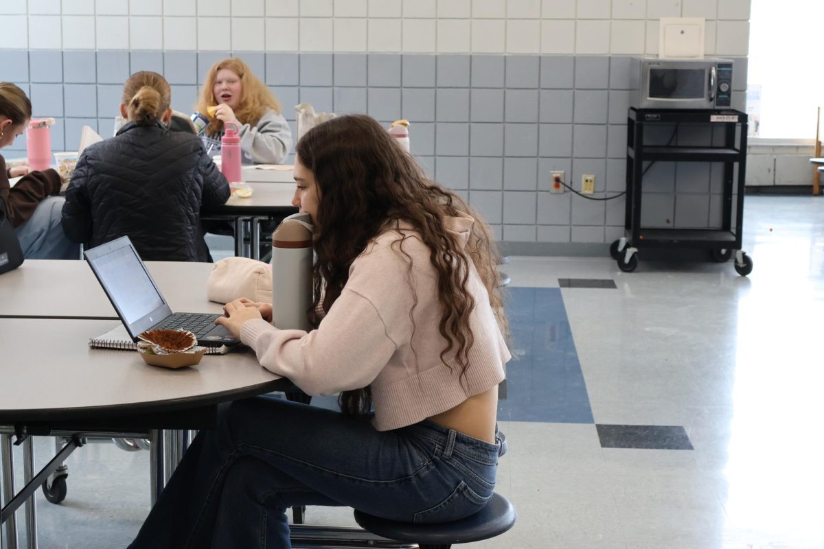 Junior Deniz Turkman works on her homework while she enjoys her lunch.