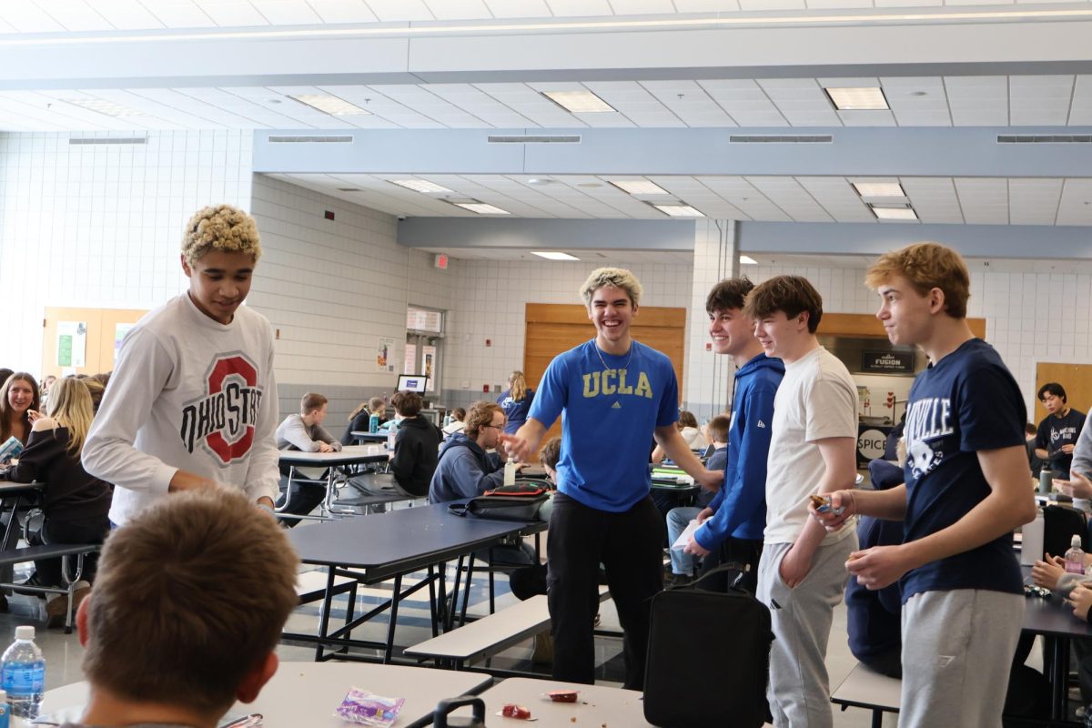 The boys laugh while they are messing around at lunch. No one has their devices and has caused many to try new things, some might be a little devious.