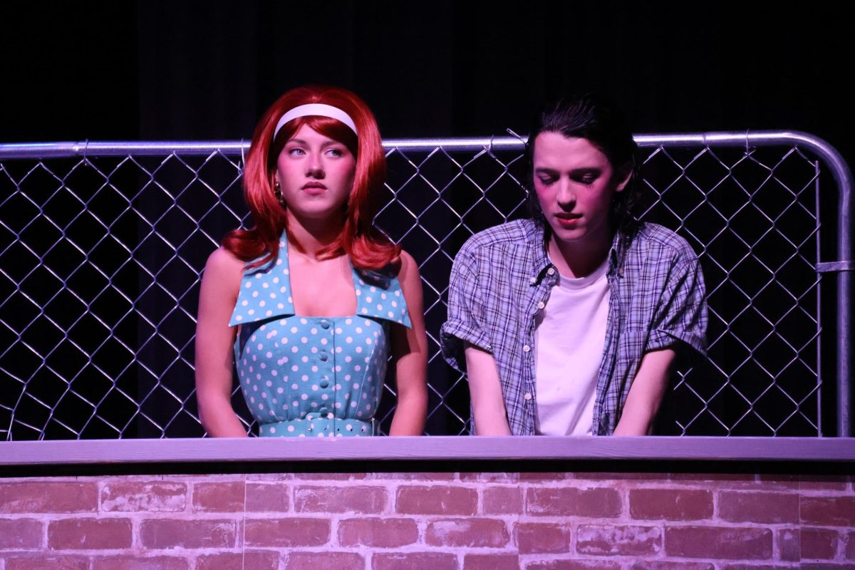 Cherry (Clara Dandurand) and Ponyboy (Sam Hannig) talk together about their life at the drive-in movies.