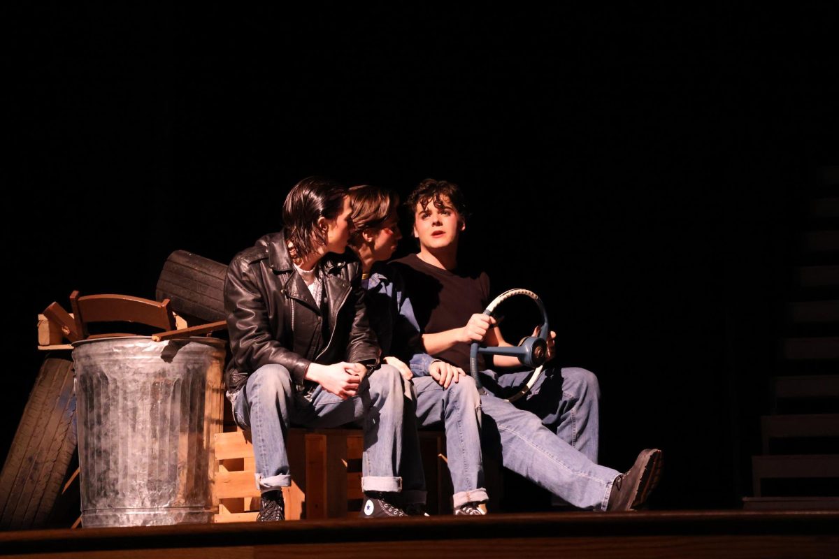 Ponyboy (Sam Hannig), Johnny (Max Holtsberry), and Dally (Jacob King) sit in the car and discuss plans.