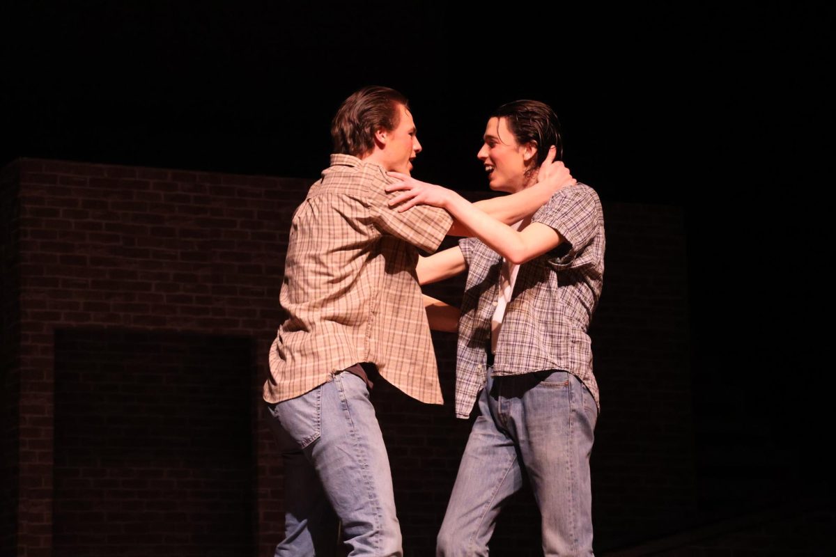 Sodapop (Grant Timmons) and Ponyboy (Sam Hannig) embrace each other as they reunite. They soon will be able to see Johnny.