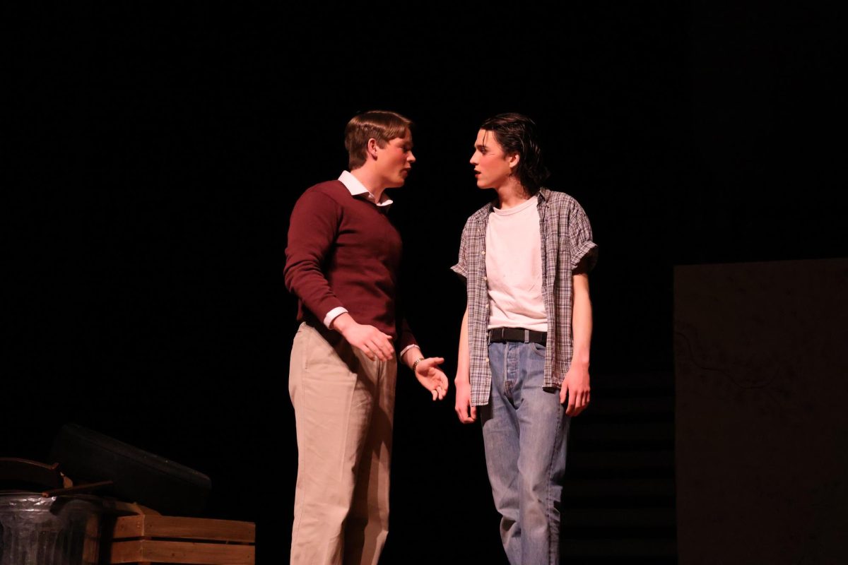 Ponyboy (Sam Hannig) and Randy (Zach Schilling) talk to each other. Later Randy feels bad about his actions.