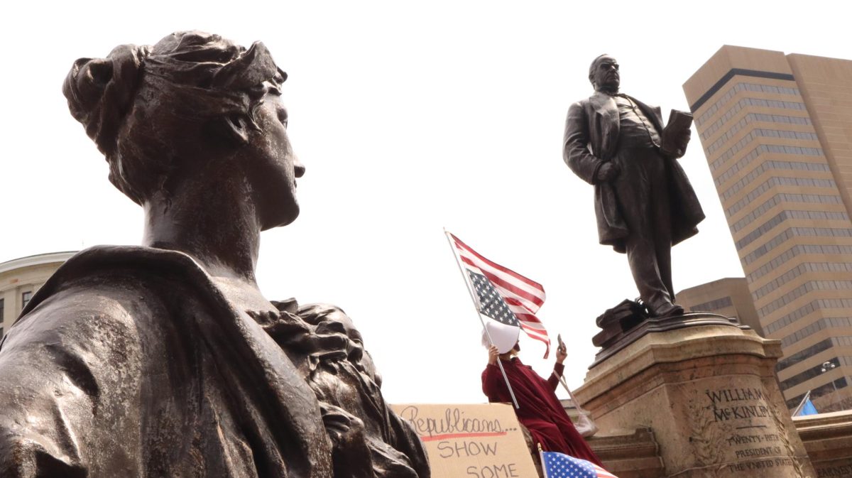 A young protester waves an upside-down American flag in front of the Ohio Statehouse as a protest against continuing restrictions on female reproductive health.