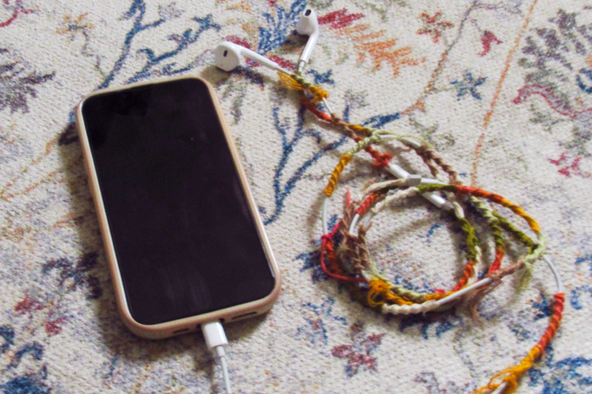 A phone with wired headphones plugged in. These wired headphones were wrapped in embroidery thread for an aesthetic element.
